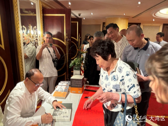 根据长篇小说《孤岛》改编的抗战题材电视剧投拍，激发了读者对原著的阅读兴趣。图为原著作者胡根为读者签名。人民网记者 富子梅摄