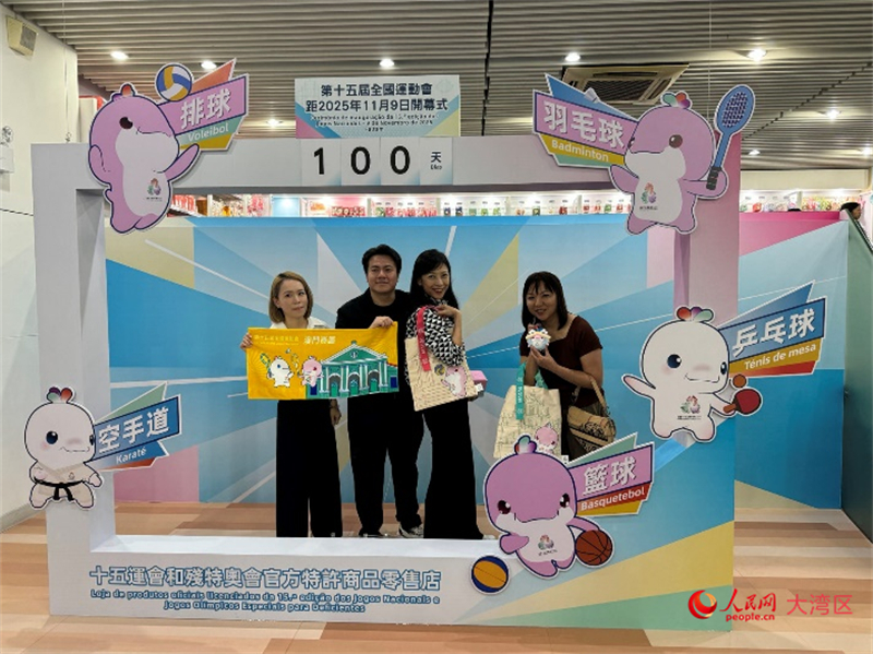 图为特许商品零售店顾客与十五运会开幕倒计时牌合影。人民网记者 富子梅摄