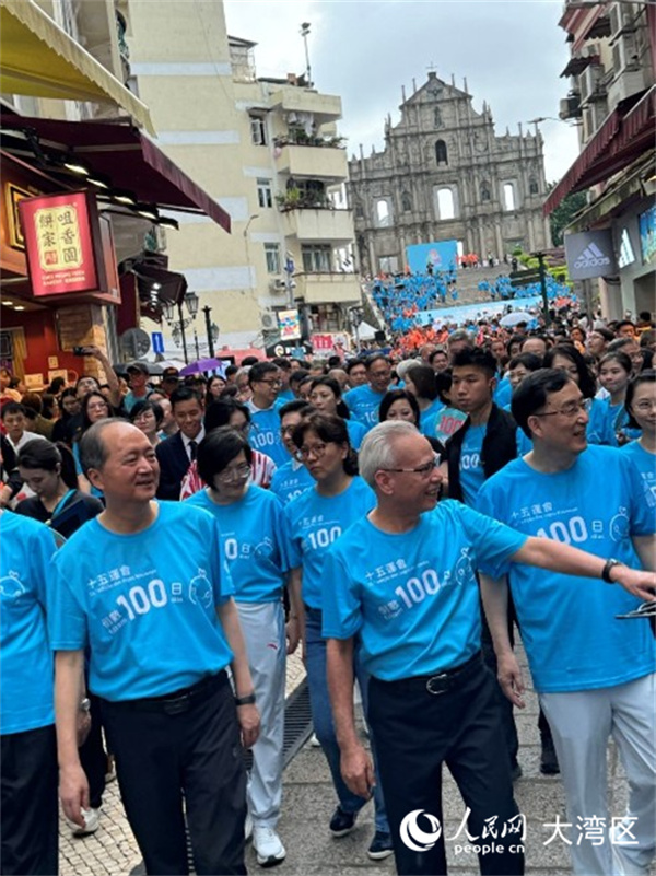 图为岑浩辉身穿蓝色运动背心，精神抖擞与众人一同从大三巴牌坊起步，参与“迎百日 健步行”活动。人民网记者 富子梅摄