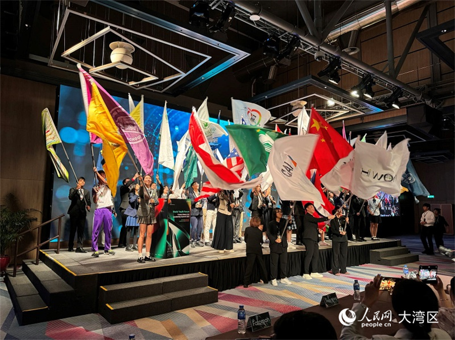 图为与会青年代表在开幕式上挥舞各自学校的旗帜。人民网记者 富子梅摄