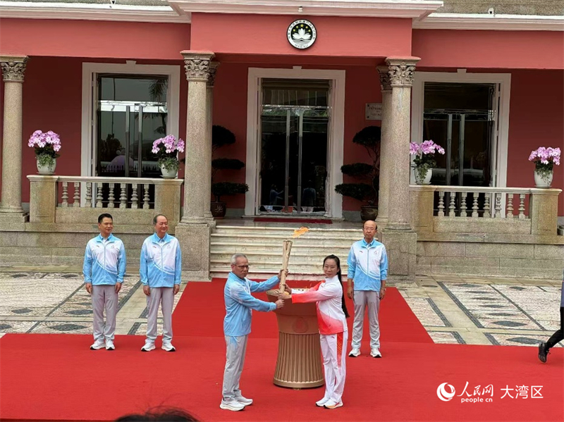 图为澳门特区行政长官岑浩辉在火种盆点燃火炬，授予第一棒火炬手澳门武术名将、2023杭州亚运武术金牌运动员李祎。人民网记者 富子梅摄