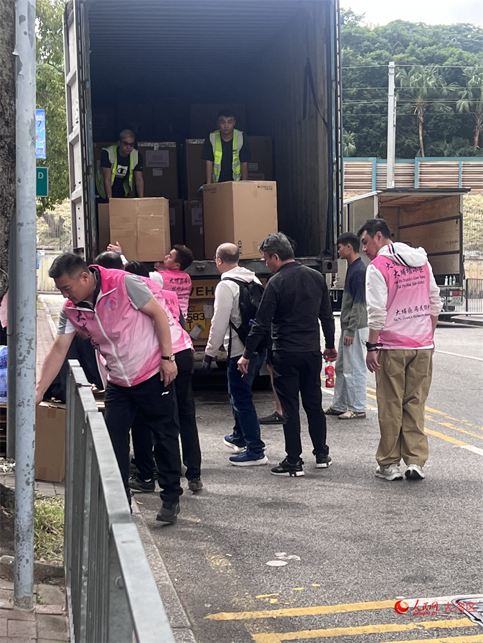 庇护中心外，关爱队和义工正在搬运物资。人民网记者 王尧摄