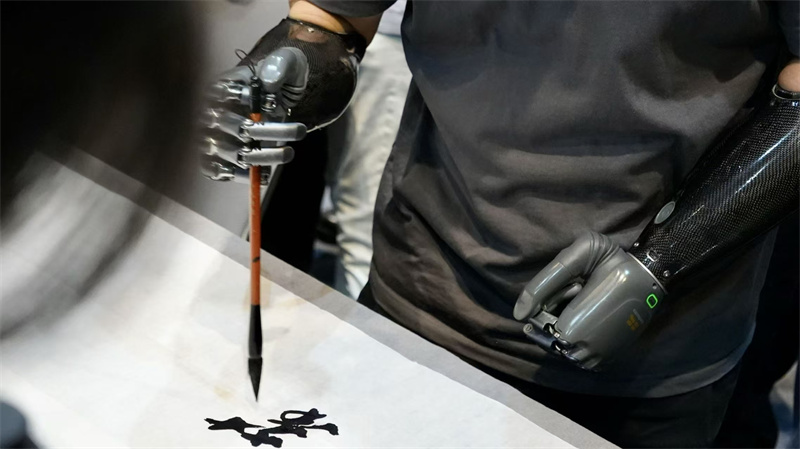 来自强脑科技的智能仿生手，依托佩戴者的神经电、肌肉电信号驱动，在现场展示书法创作。人民网 吴宇扬扬摄