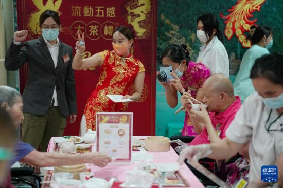5月24日,在香港松悦园耆和护养院,香港乐龄社企“软餐侠”的职员们扮演成“茶楼”经理、厨师和接待员,为老人家提供沉浸式茶楼就餐体验。新华社发(王申 摄)