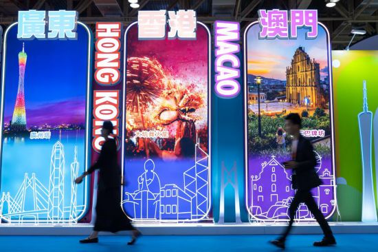 4月25日，参观者从第十三届澳门国际旅游（产业）博览会大湾区展板前经过。新华社发（张金加摄）