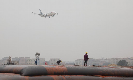 　　2025年1月23日，一架准备降落的飞机经过白云机场扩建工程施工现场。新华社记者 田建川 摄