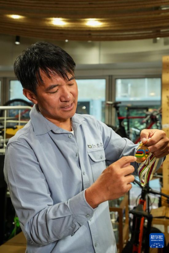 10月13日，在香港荃湾环贸广场，黄金宝在他经营的单车店内介绍奖牌。新华社记者 朱炜 摄