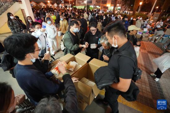 11月27日，义工在宏福苑附近向受火灾影响的市民派发物资。新华社发（吕小炜摄）