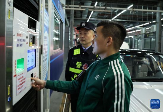 12月23日零时，“粤车南下”入境香港市区的通关车主曹先生（前）在“一站式”通道办理通关手续。新华社记者 黄国保 摄