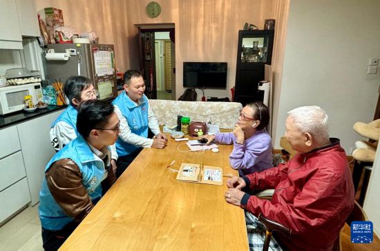 　　11月18日，穆家骏（前左）与关爱队成员在湾仔利昌大厦走访社区长者。新华社记者 陈铎 摄